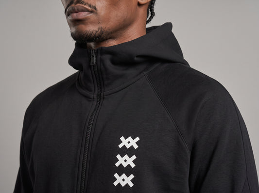 Detalle de la chaqueta del tracksuit AMV negro con cierre y tres logos AMV blancos