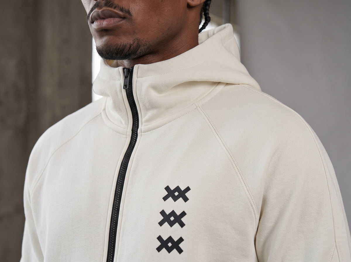 Detalle de la chaqueta del tracksuit AMV blanco con cierre negro y logos AMV