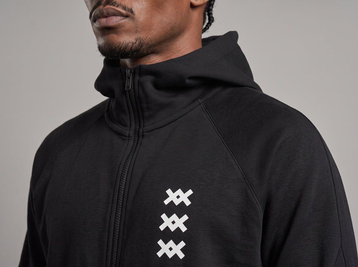 Detalle de la chaqueta del tracksuit AMV negro con cierre y tres logos AMV blancos