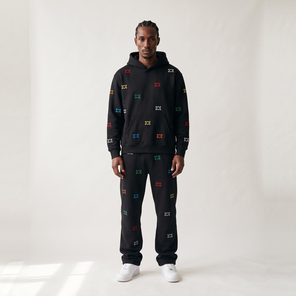 Multi Logo AMV 1/1: hoodie y pantalón negros con logos AMV bordados en colores, vista de frente, pieza única